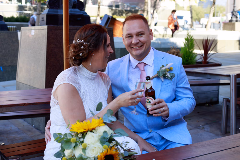 The couple seated together at a bar on the edge of Millennium Square, relaxed and smiling between moments.