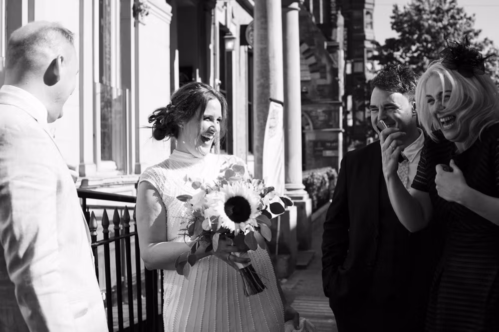 Bride laughing on the steps of the Lost & Found Club in Leeds as she greets family at the end of portraits.