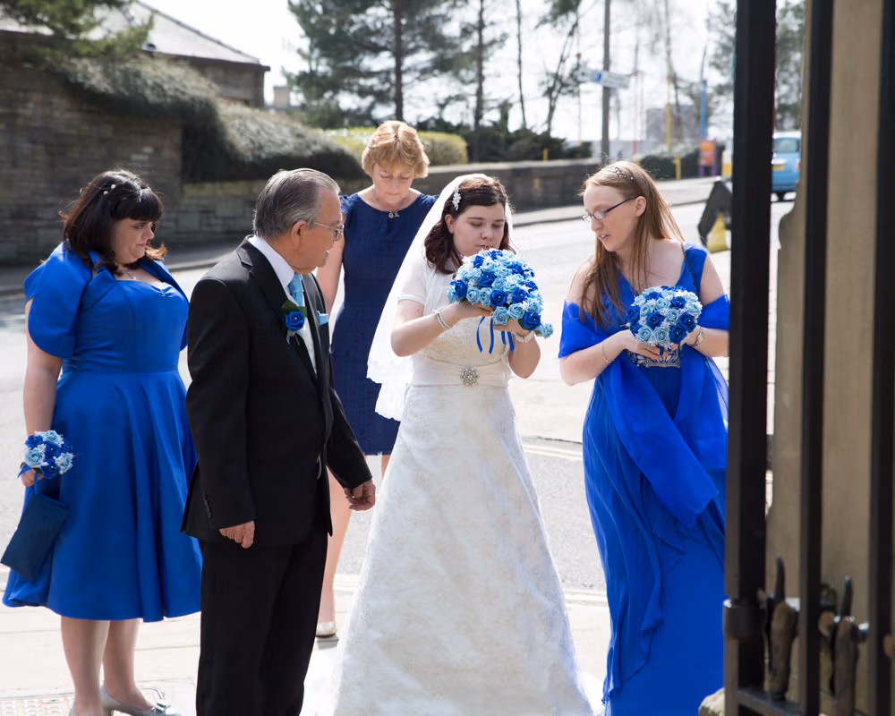Bride makes final adjustments surrounded by family at the gate of Halifax Minster