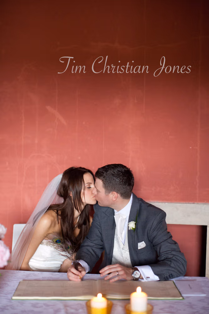 Bride and groom share a kiss at the signing table during the ceremony