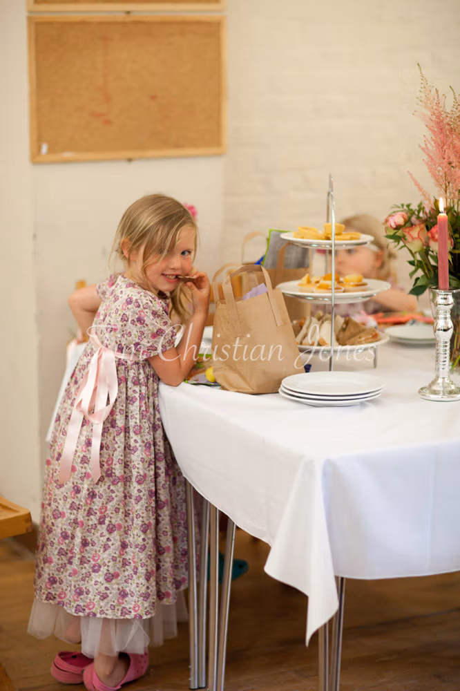Flower girl reaching for snacks from the food table at the reception